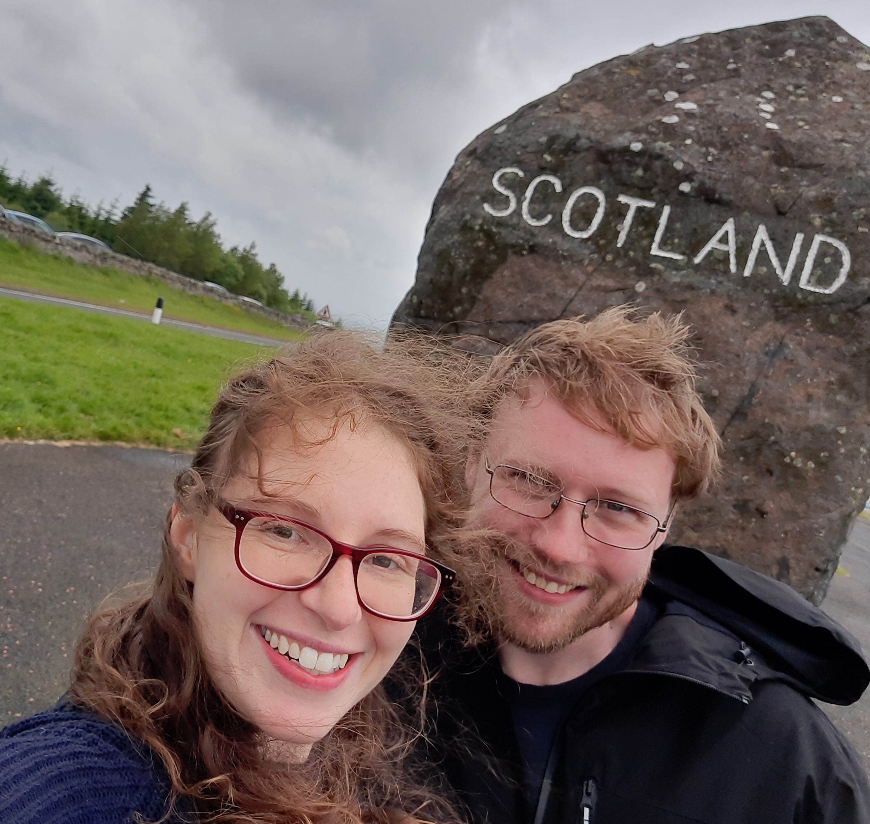Katelyn and Geoff with a Border stone marked Scotland in the background